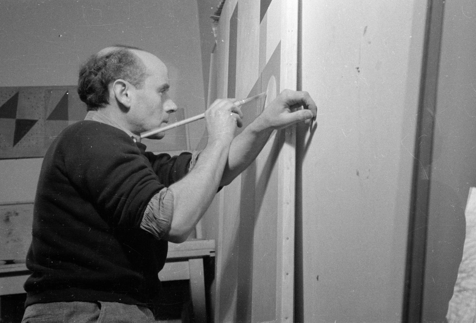 A black and white photograph of Ben Nicholson - he is working on a canvas
